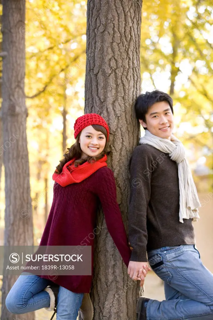 Young Couple Leaning Against a Tree Holding Hands