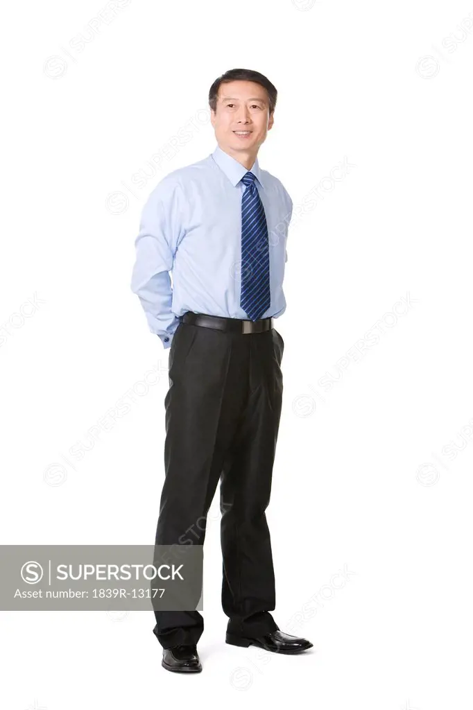 Mature businessman standing with arms behind back