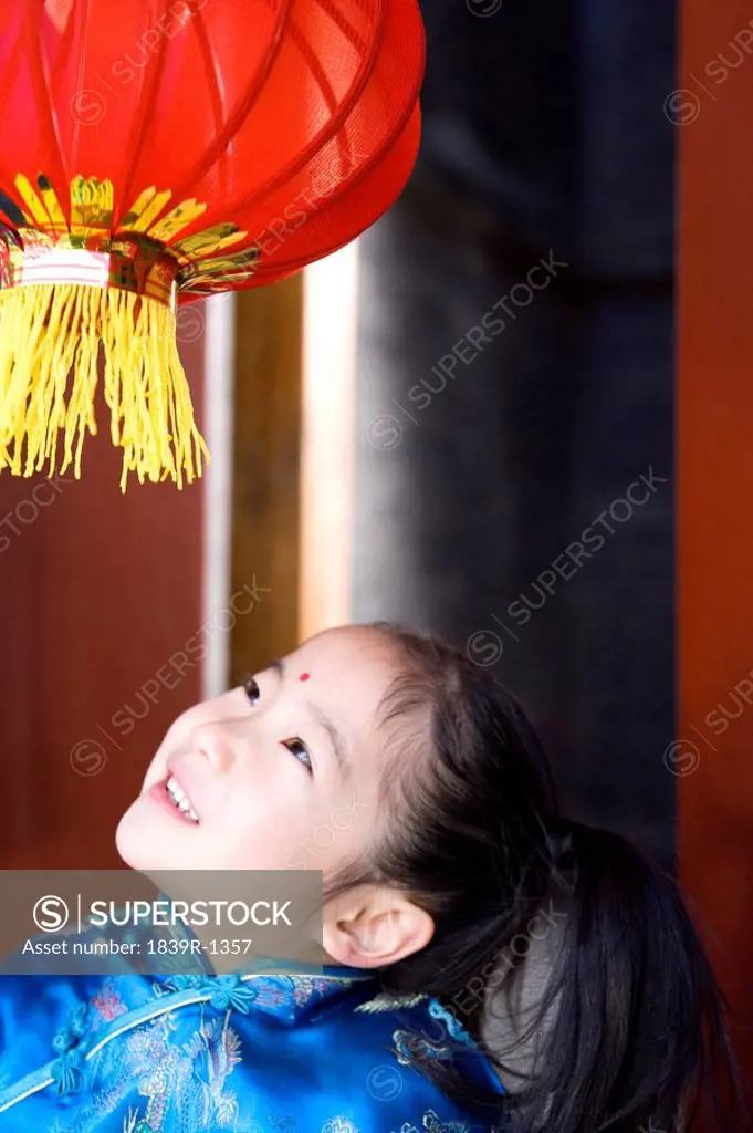Girl In Traditional Clothing Looking Up At Lantern