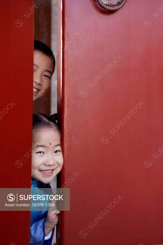 Mischievous Children Peeking Around Door