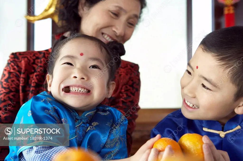 Traditionally Dressed Children And Mature Woman Playing