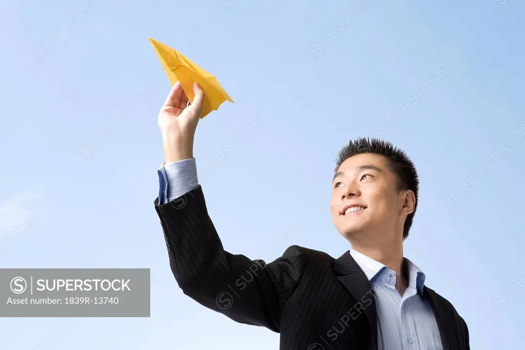 Businessman flying paper airplane