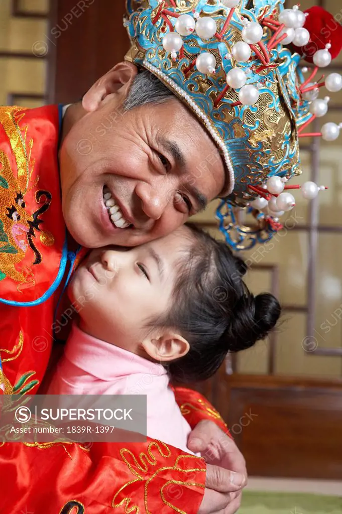Grandfather In Traditional Costume Hugging His Granddaughter