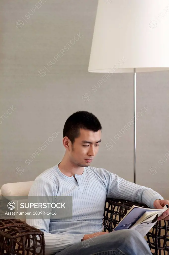 Man Sitting And Reading Magazine