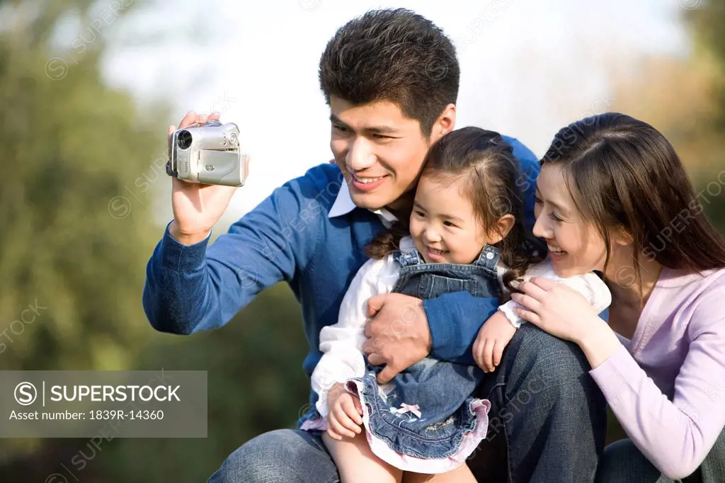 Young family making a home video at the park