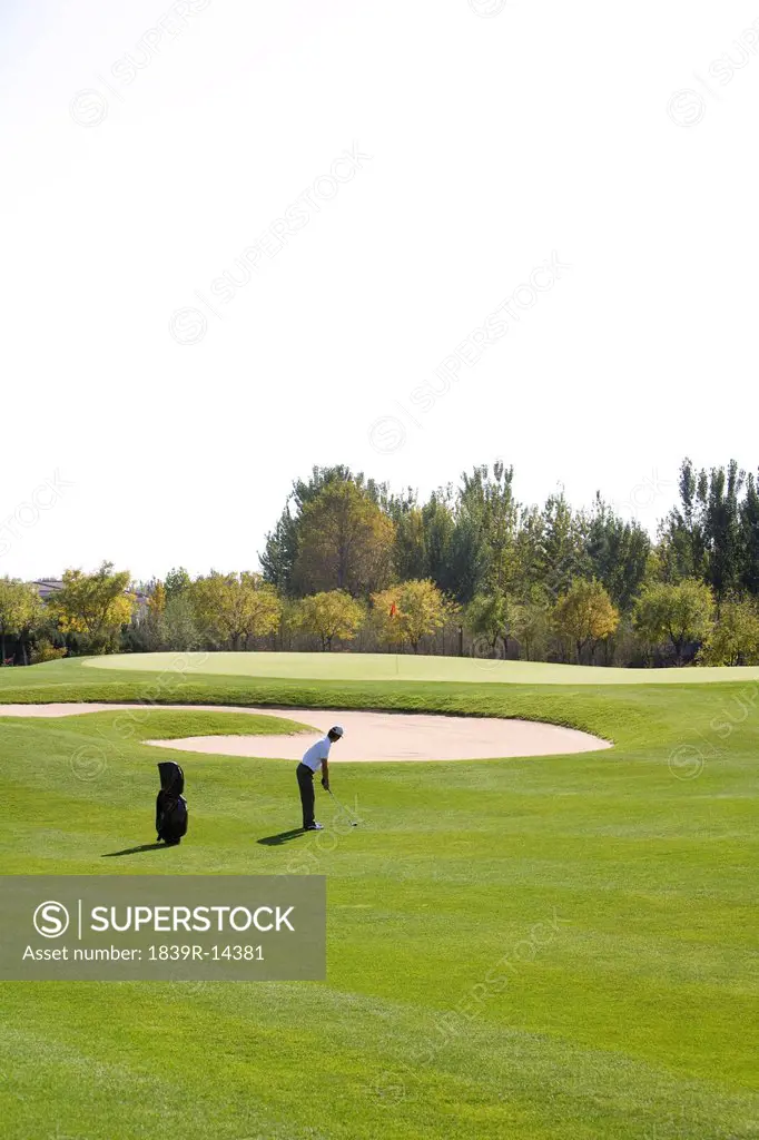 Man swinging golf club on golf course