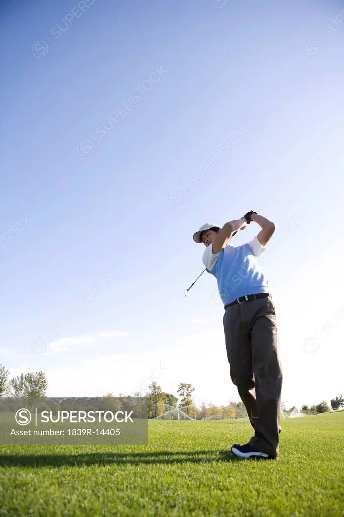 Man swinging golf club on golf course