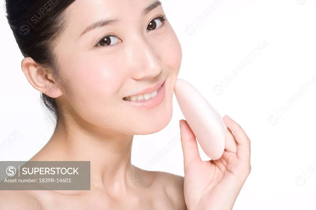 Beauty shot of a young woman holding a powder puff