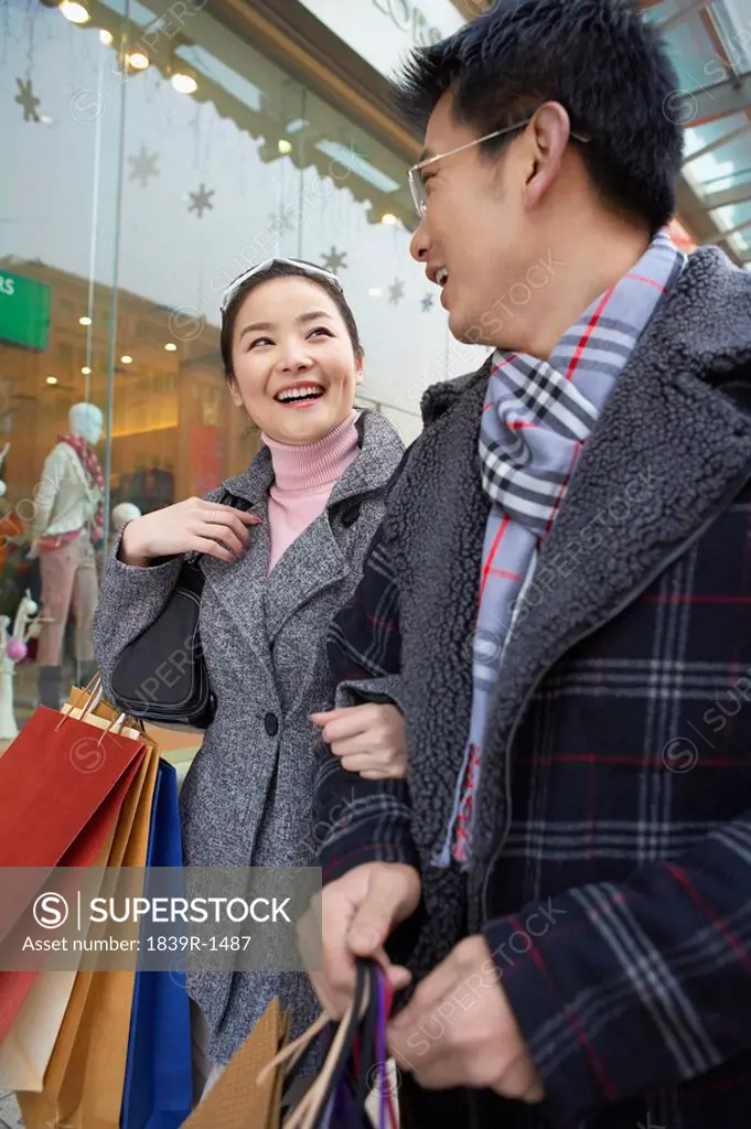 Couple With Linked Arms Carrying Shopping Bags