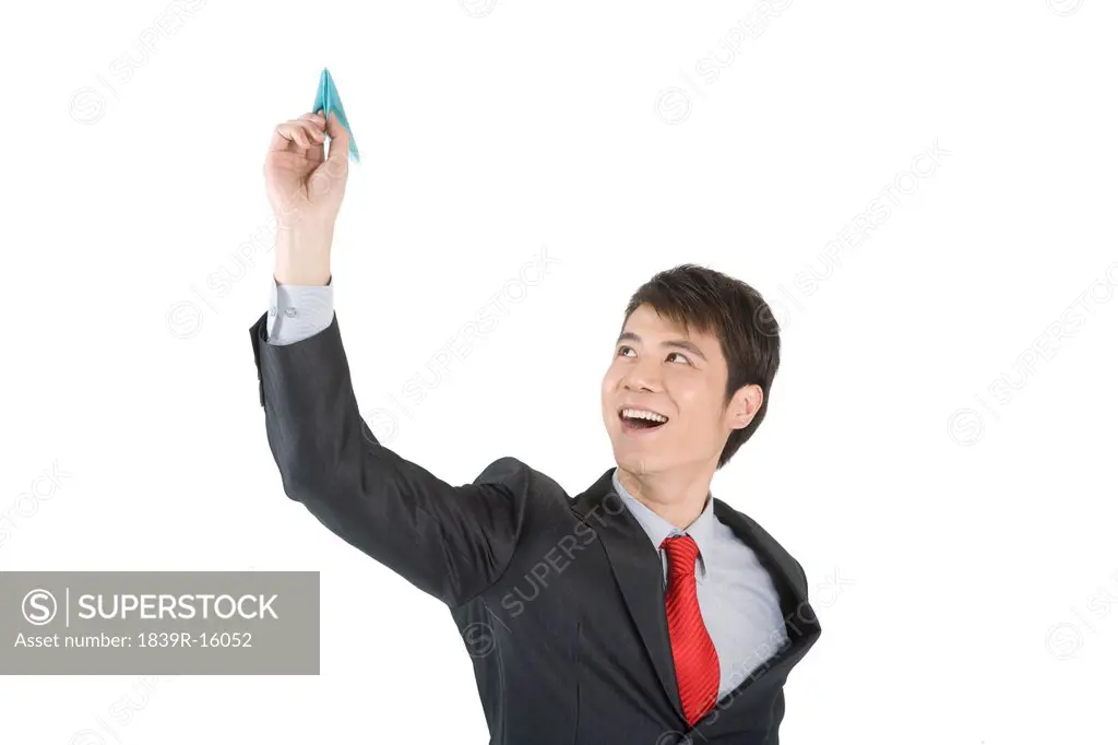 Young businessman playing with a paper airplane