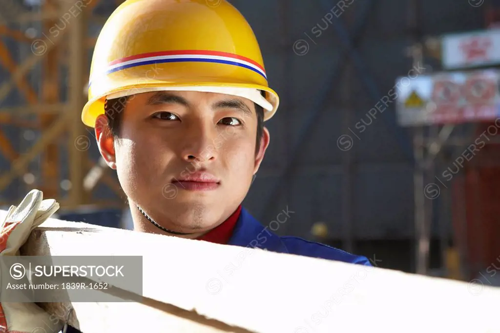 Man In Construction Site With Hard Hat And Planks Of Wood