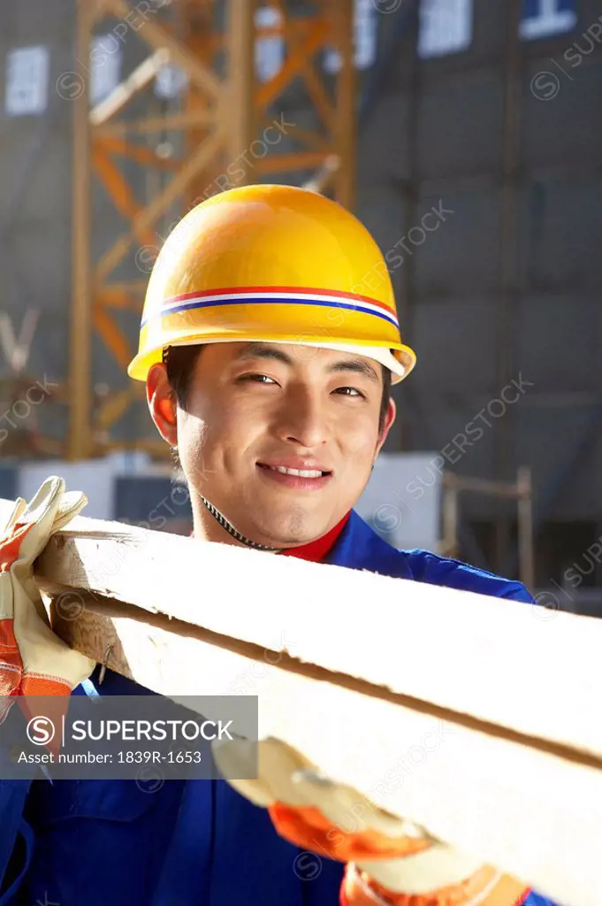 Man In Construction Site With Hard Hat And Planks Of Wood