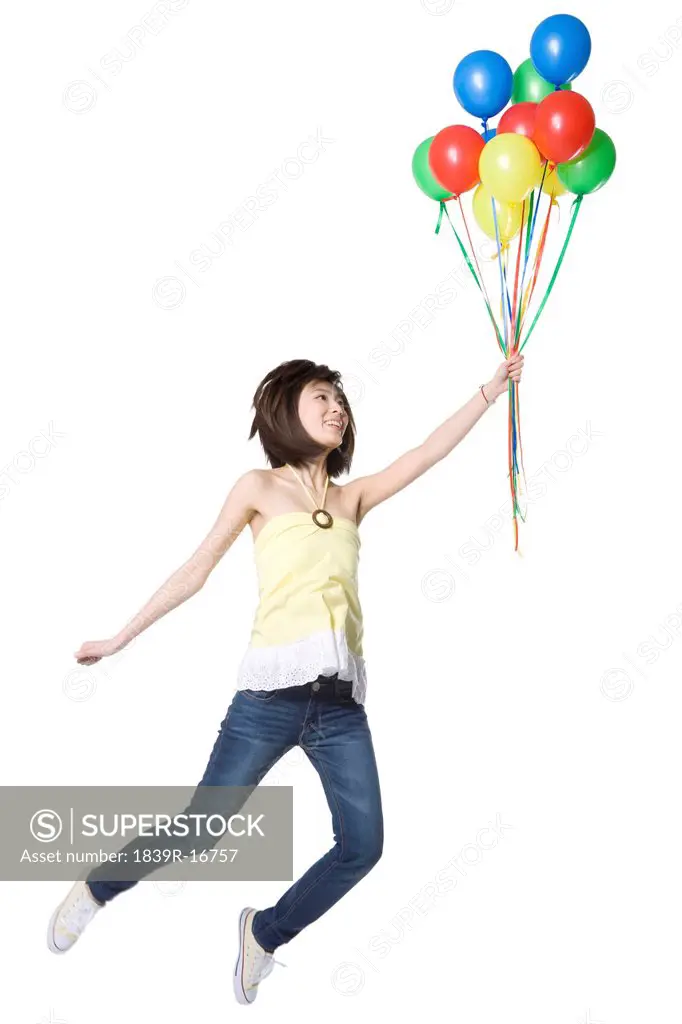 Young woman floating off with a bunch of balloons