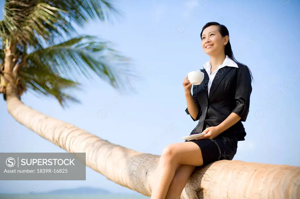 Businesswoman having a cup of coffee on the beach