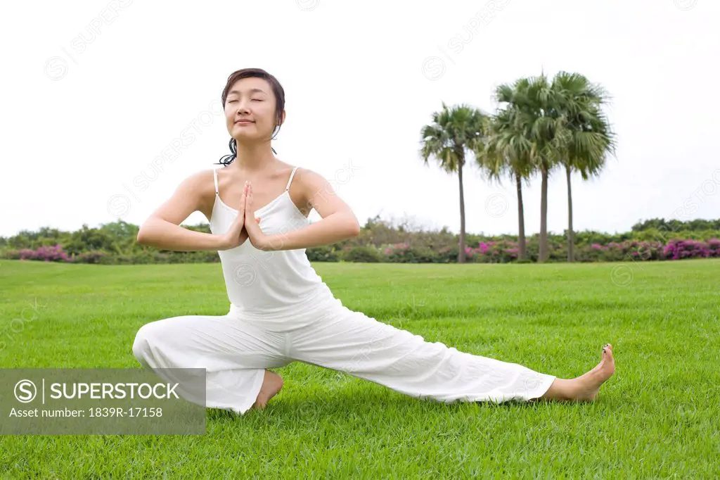 A woman practicing yoga on a grass field