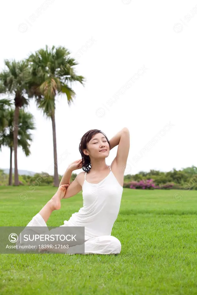 A woman practicing yoga on a grass field