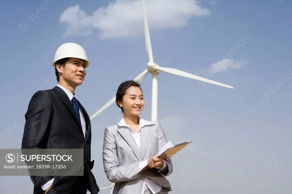 Businesspeople or engineers in front of wind turbines