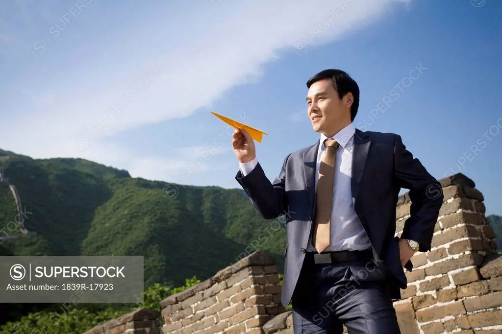 Businessman on the Great Wall holding paper airplane