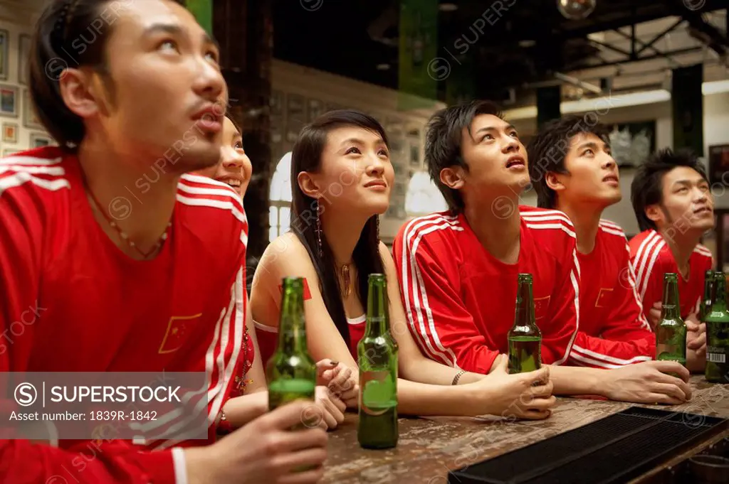 Young People Leaning On Bar Watching Game