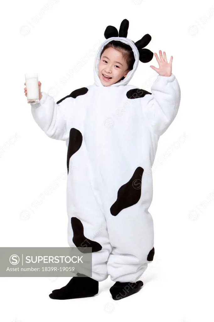 Cute girl in a cow costume with a glass of milk