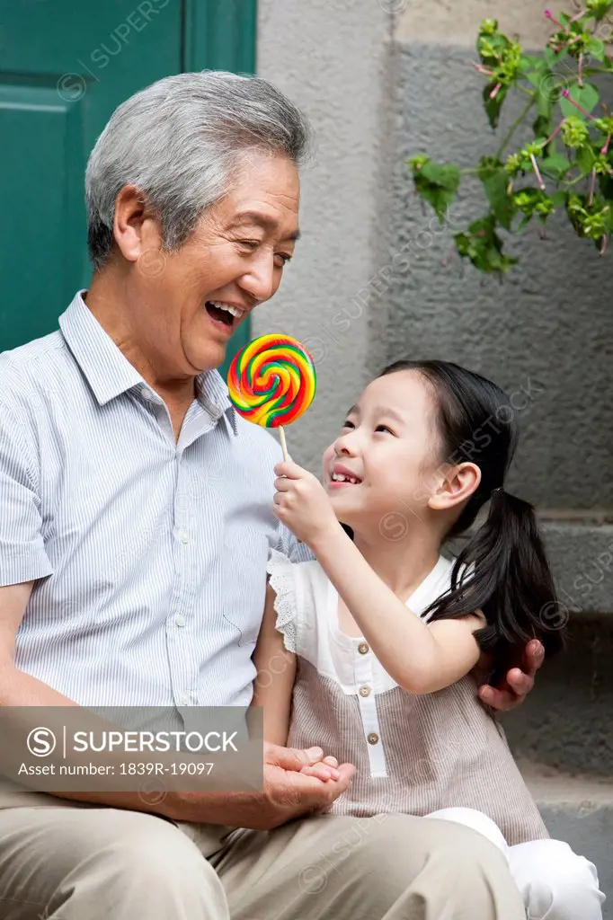 Chinese Grandfather and Grandaughter with lollipop on front stoop