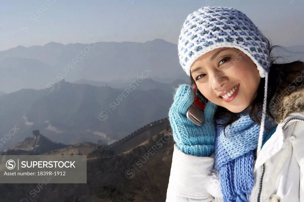 Young Woman On The Great Wall Of China, Talking On Her Cellphone