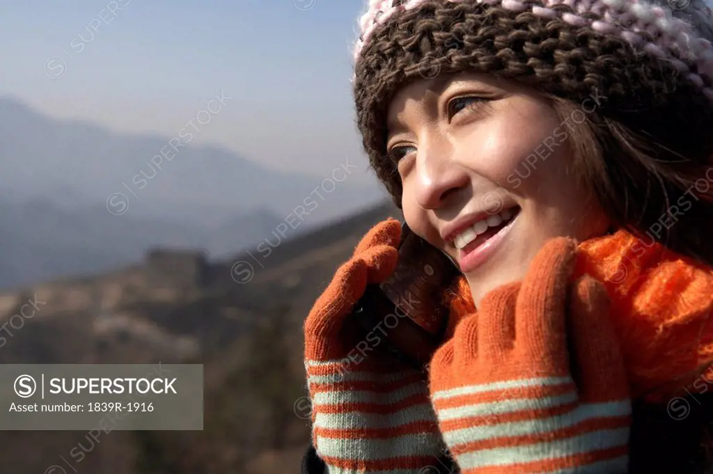 Young Woman On The Great Wall Of China, Talking On Her Cellphone