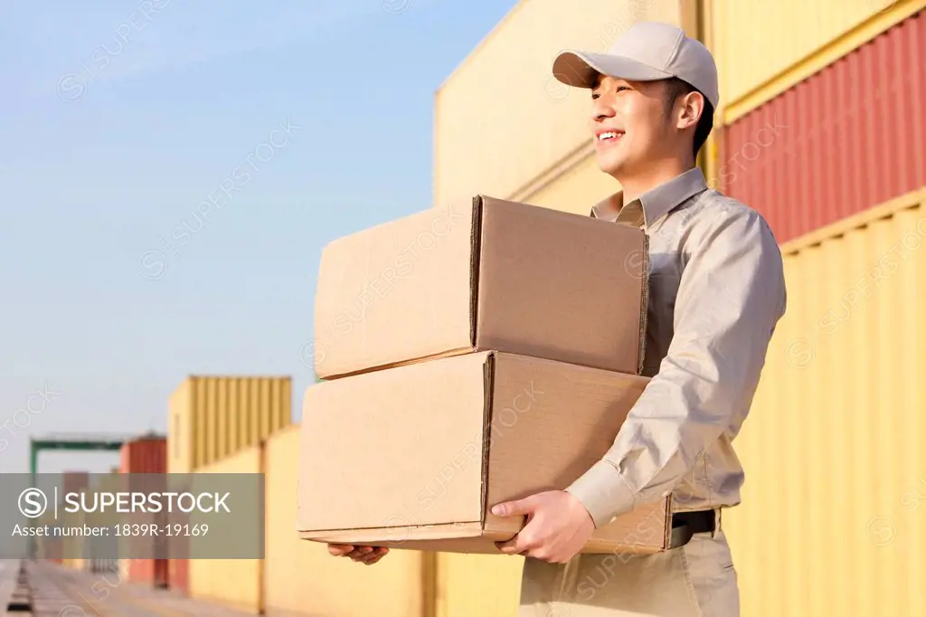 shipping industry worker carrying cardboard boxes