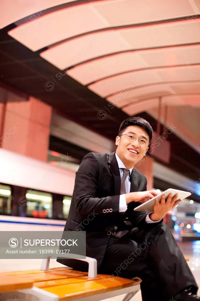 Young businessman using a digital tablet at the train station