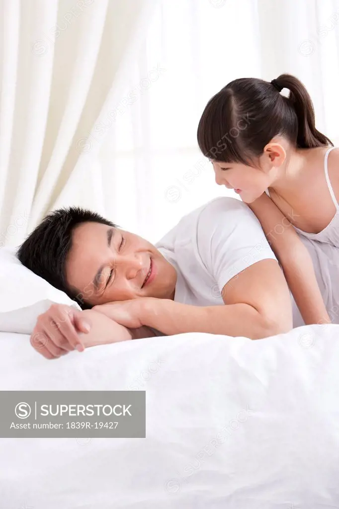 Father and daughter having fun in bed