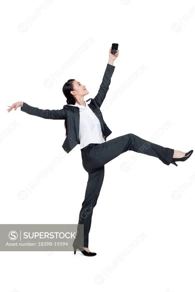 A dancing businesswoman holding a mobile phone