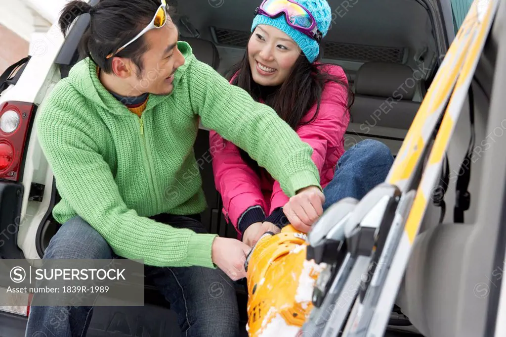 Man Helping Woman To Put On Her Ski Boots