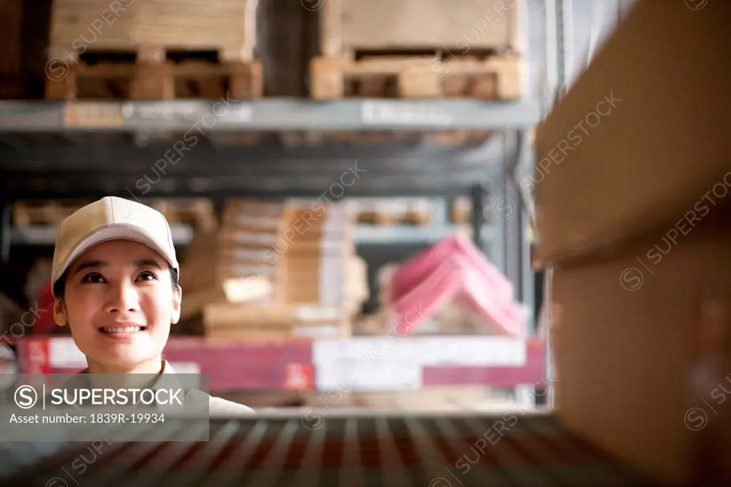 Female Chinese warehouse worker looking at boxes