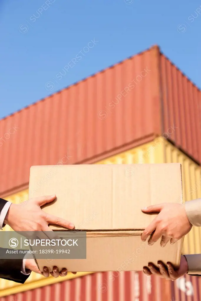 Businessman and shipping industry worker giving and receiving a cardboard box