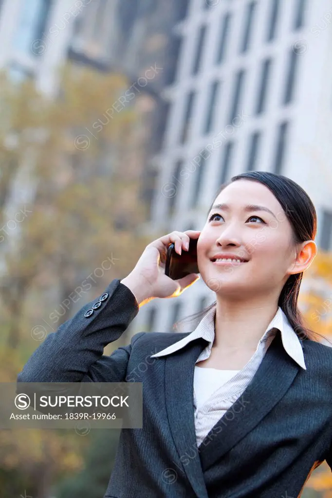 Businesswoman outside office buildings on her mobile phone