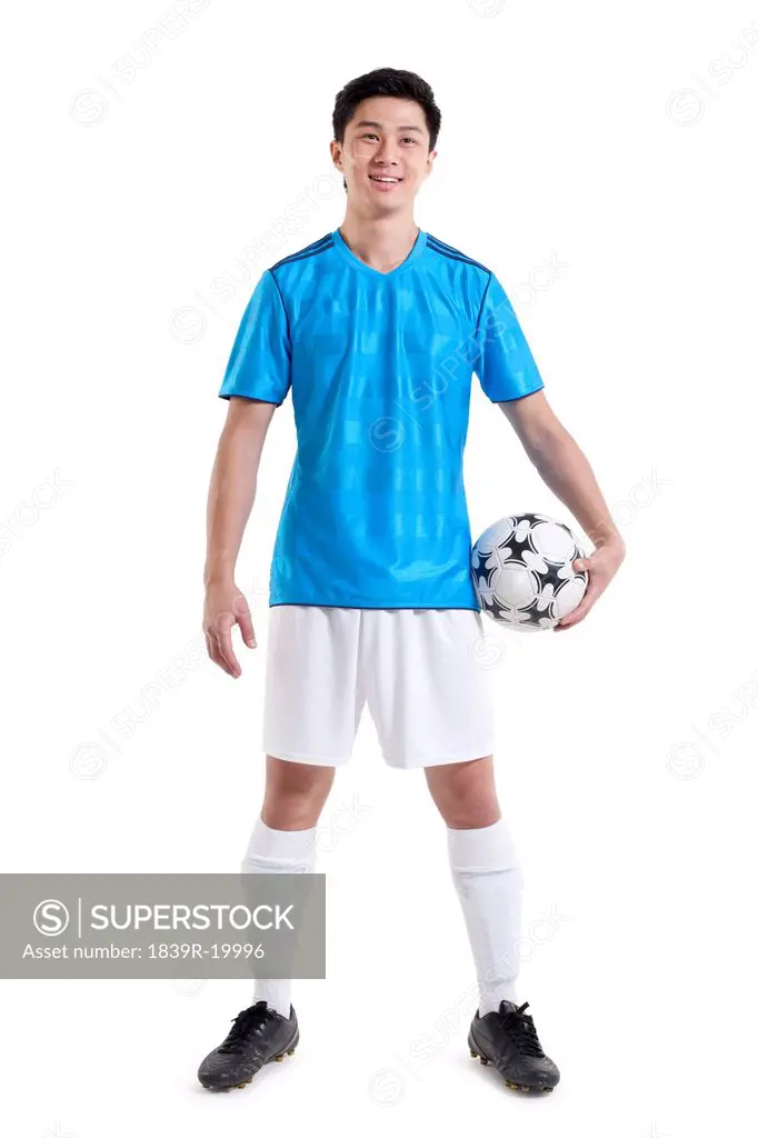 Soccer player standing holding a ball