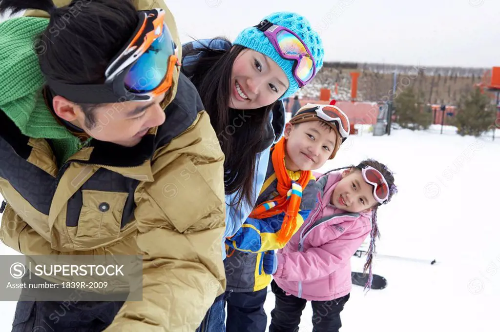 Family On Ski Field With Arms Around Each Other