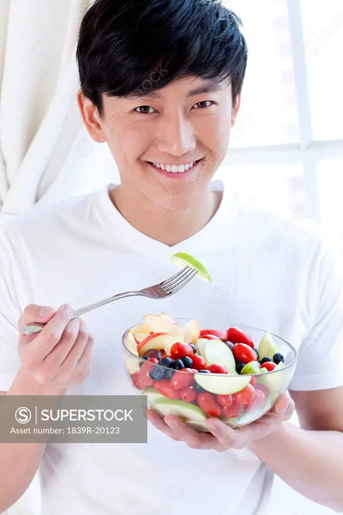 Young man eating fruit salad