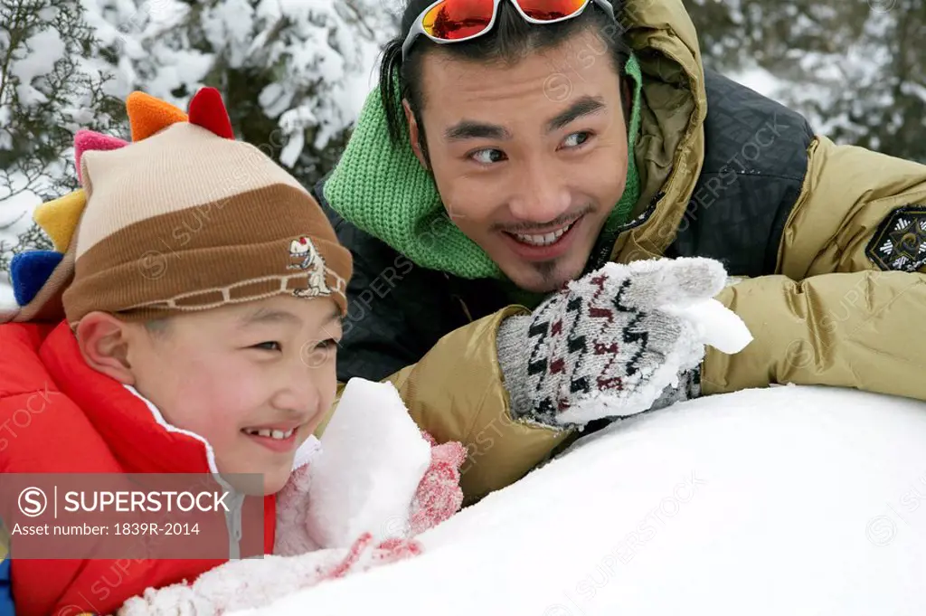 Father And Son Making Snowballs, Hiding Behind Snow Wall