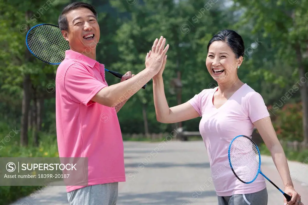 Mature couple playing badminton in park