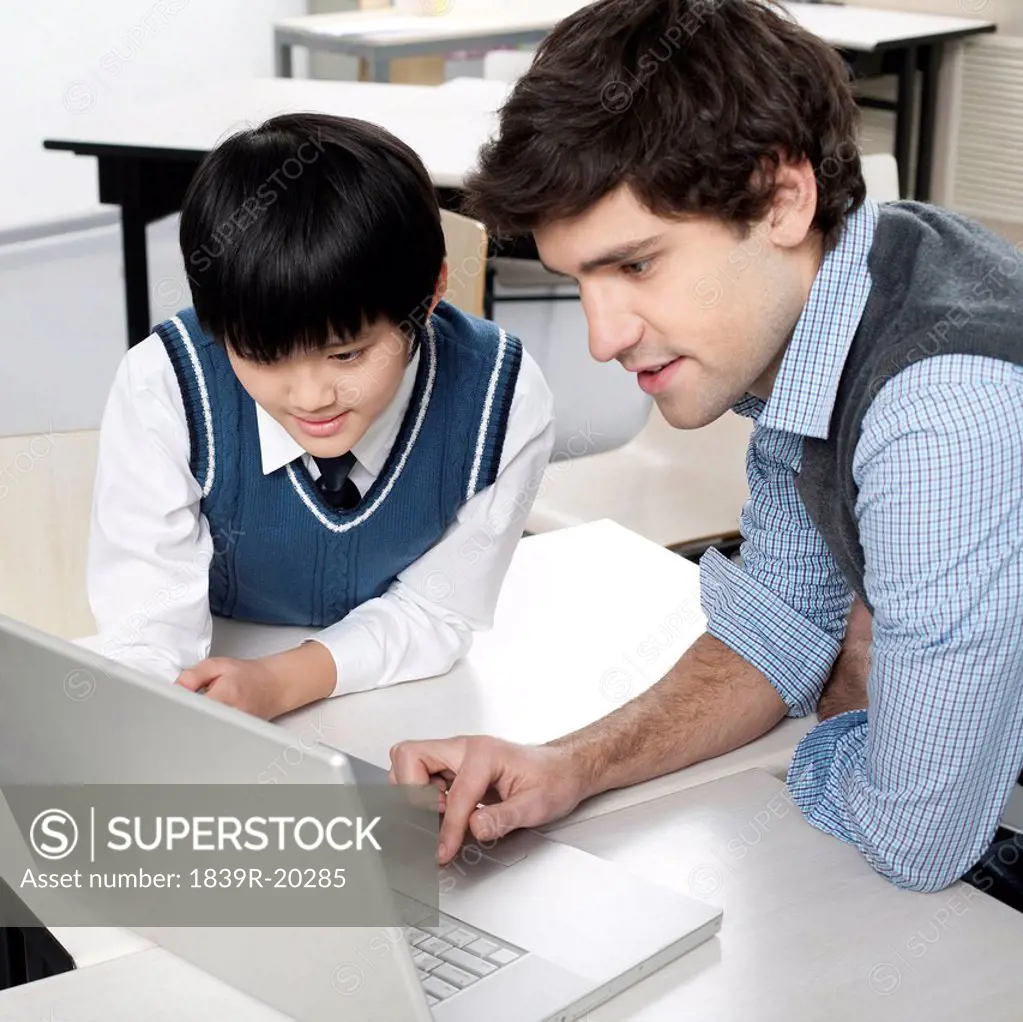 Student and teacher using computer together