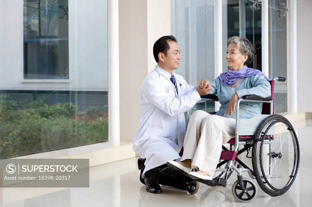 Doctor Comforts a Senior Woman in a Hospital Corridor