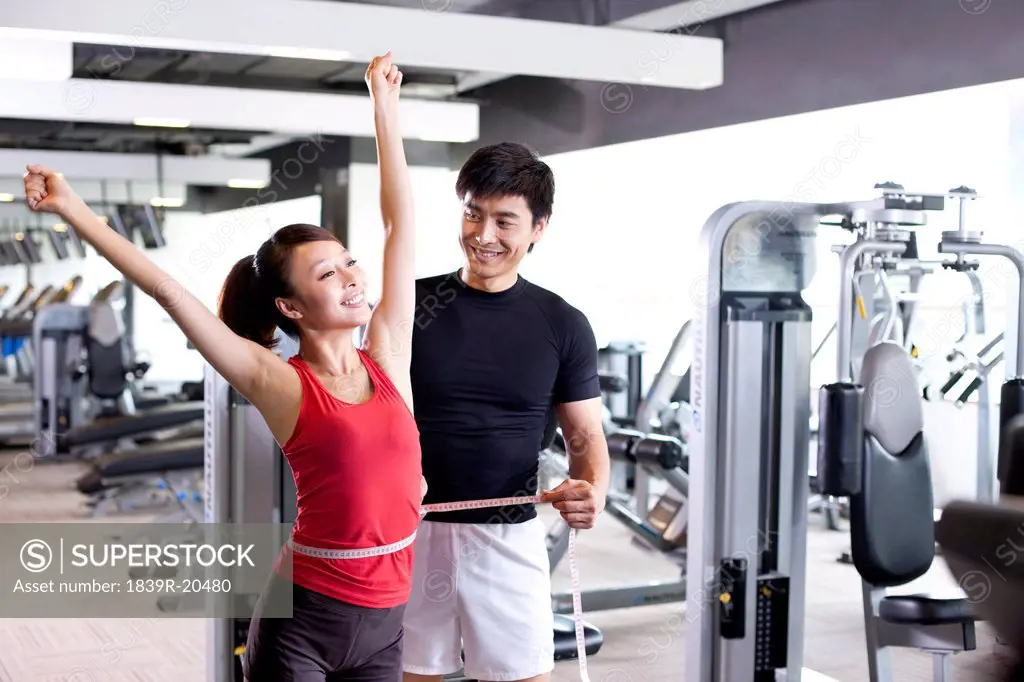 Young Man Measuring Young Woman at Gym