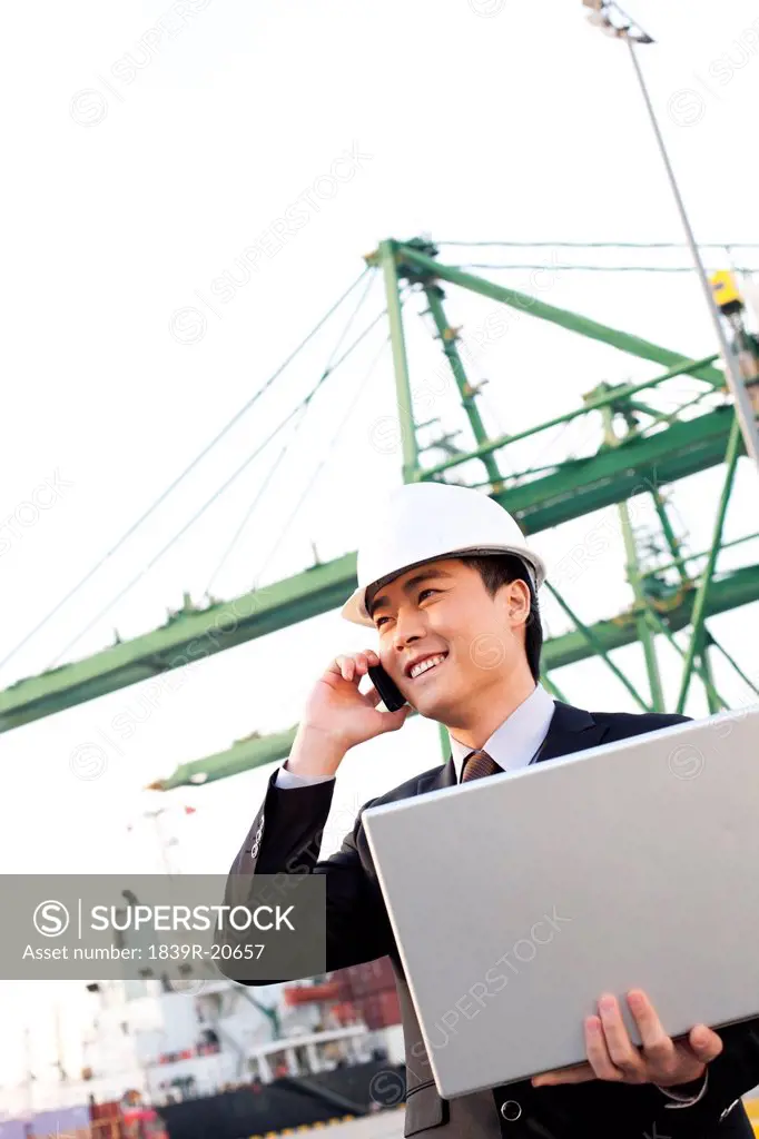 businessman using a laptop and mobile phone at a shipping port