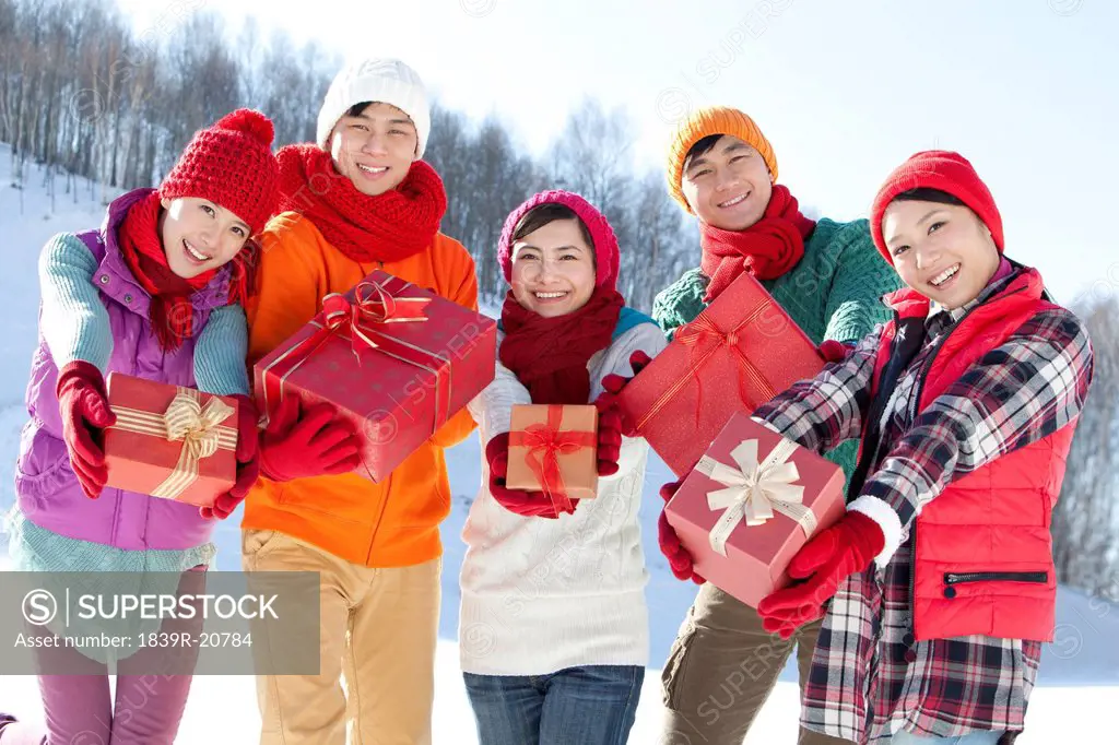 Happy young people holding gift boxes