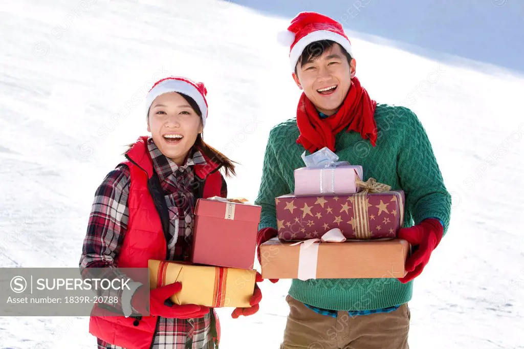 Young couple holding Christmas gift boxes