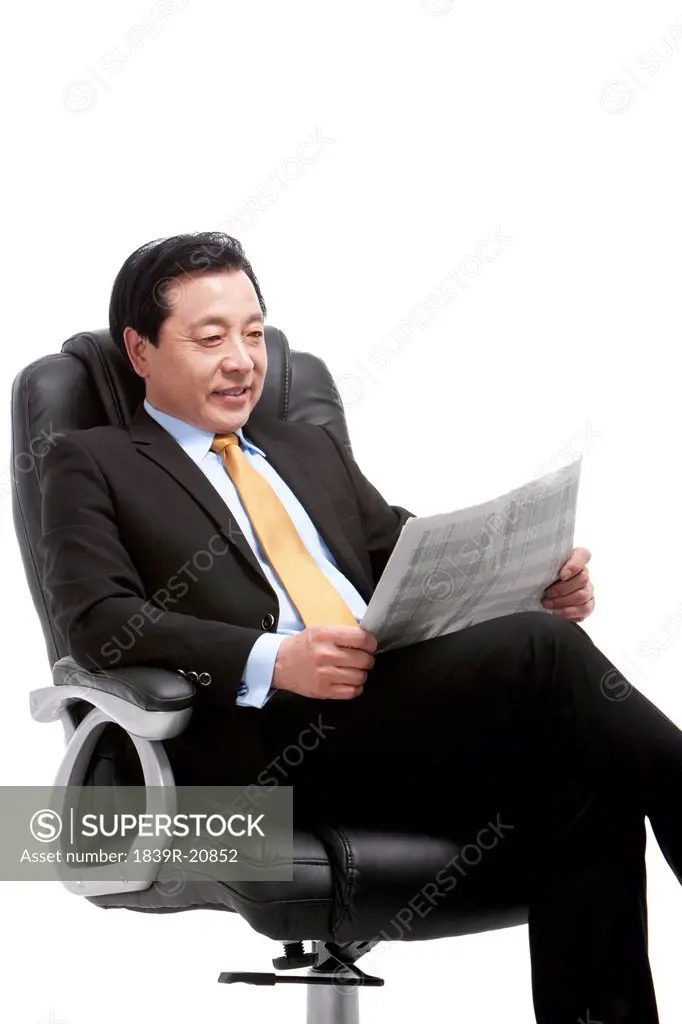 Senior businessman reading newspaper on director´s chair