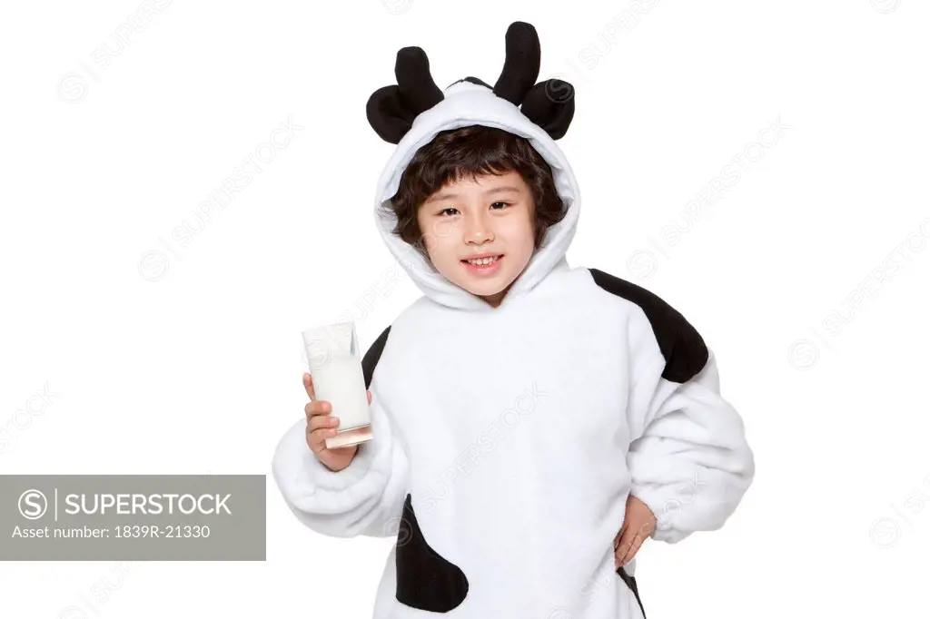 Cute boy in a cow costume with a glass of milk