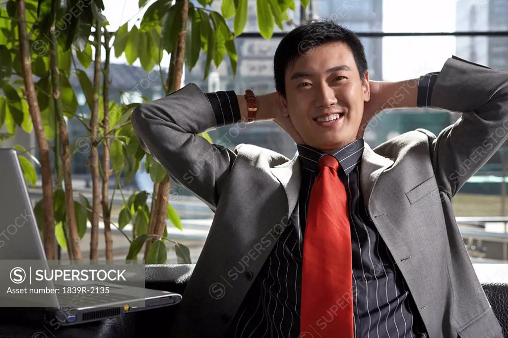 Businessman Sitting With Hands Behind His Head