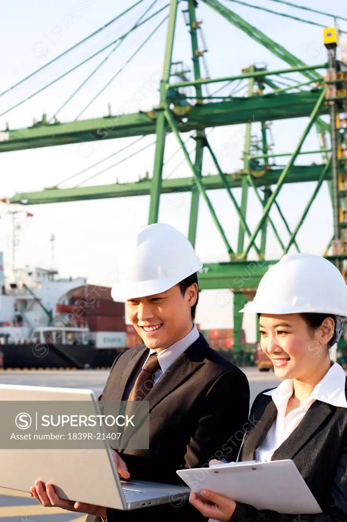 businesspeople using a laptop at a shipping port